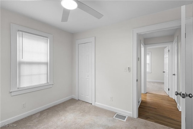 unfurnished bedroom with ceiling fan, visible vents, baseboards, a closet, and carpet