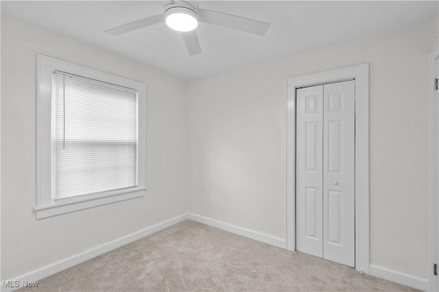 unfurnished bedroom featuring carpet floors, a closet, baseboards, and a ceiling fan