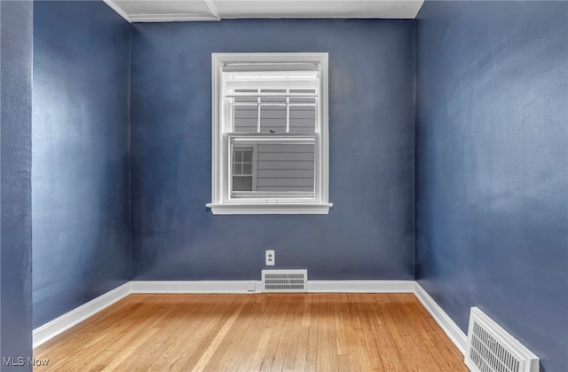 spare room featuring visible vents, baseboards, and hardwood / wood-style flooring