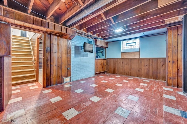 finished basement with wainscoting, wood walls, and stairway