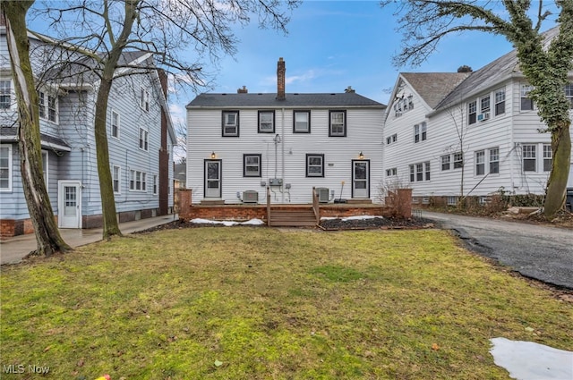 back of property featuring a lawn and a chimney