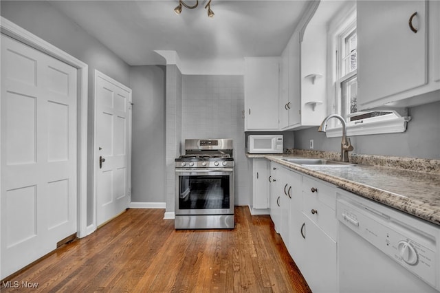 kitchen with white appliances, dark wood-style floors, light countertops, white cabinetry, and a sink