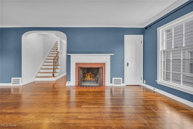 unfurnished living room with a fireplace, visible vents, and wood finished floors