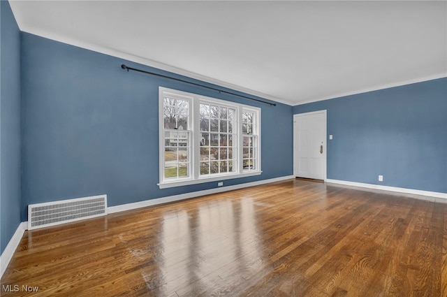 spare room featuring visible vents, baseboards, and wood finished floors