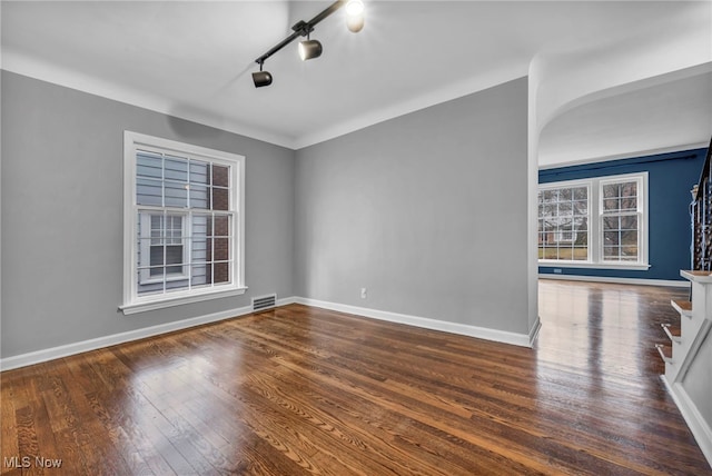 unfurnished room featuring stairway, wood-type flooring, visible vents, and baseboards