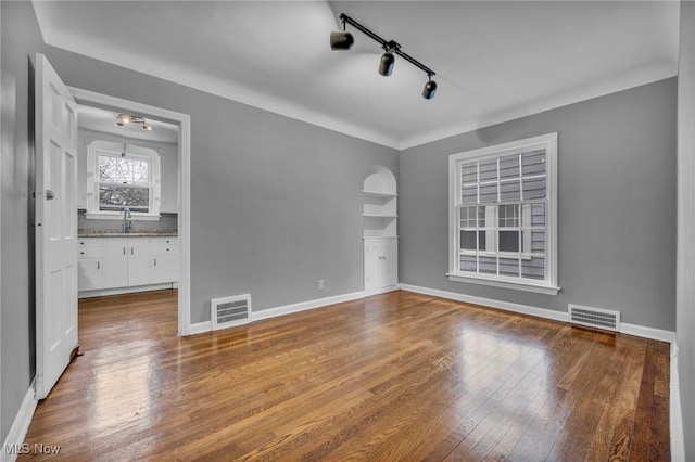 unfurnished room with wood-type flooring, visible vents, and baseboards