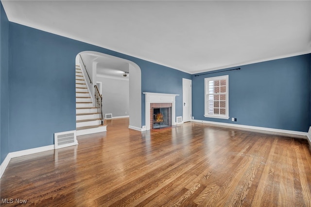 unfurnished living room with a fireplace, wood finished floors, visible vents, and baseboards