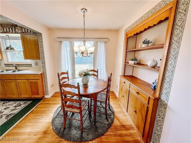 dining area featuring light wood-style floors, a notable chandelier, and baseboards