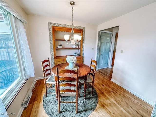 dining area featuring baseboards, a notable chandelier, and light wood finished floors