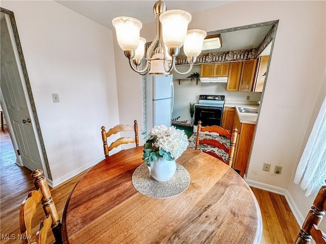 dining space with a chandelier, baseboards, and light wood-style floors