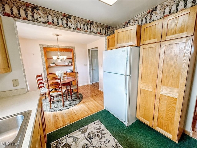 kitchen featuring hanging light fixtures, light brown cabinetry, an inviting chandelier, freestanding refrigerator, and a sink