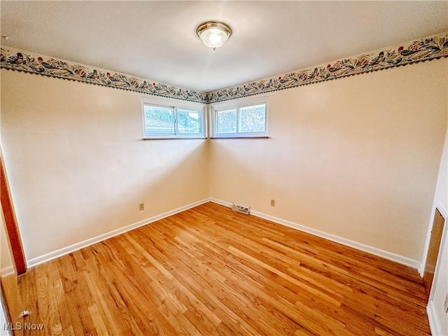 unfurnished room with light wood-type flooring, visible vents, and baseboards