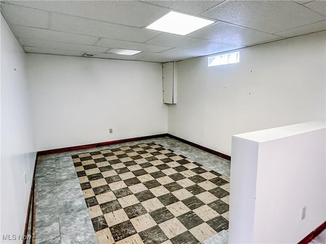 below grade area with baseboards, a drop ceiling, and tile patterned floors