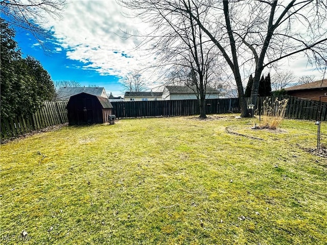 view of yard featuring a fenced backyard, an outdoor structure, and a storage shed