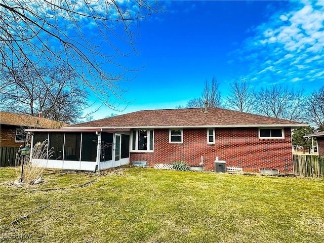 rear view of property with brick siding, a yard, central air condition unit, a sunroom, and fence