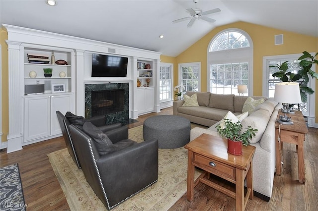 living area featuring dark wood finished floors, visible vents, a high end fireplace, vaulted ceiling, and ceiling fan