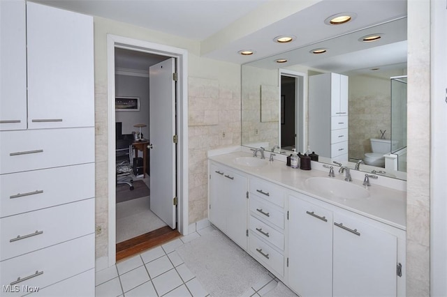 bathroom with tile patterned flooring, a sink, tile walls, and double vanity