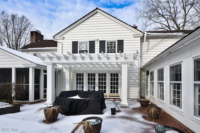 snow covered property with a patio, a sunroom, french doors, a pergola, and a chimney