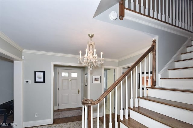 entryway featuring a notable chandelier, wood finished floors, baseboards, stairs, and crown molding