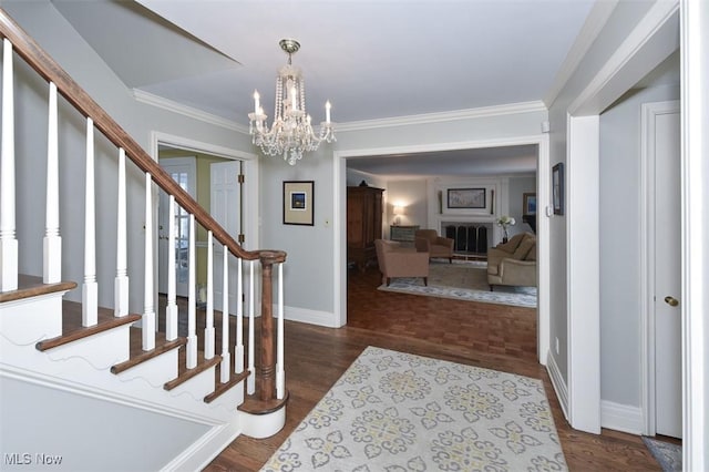 foyer featuring baseboards, ornamental molding, dark wood-style flooring, stairs, and a chandelier