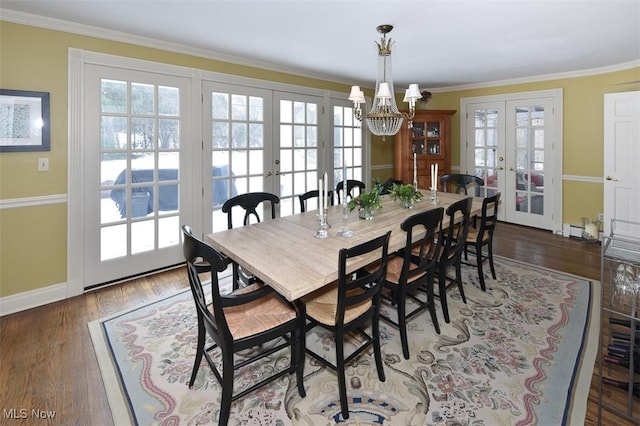 dining space with french doors, crown molding, wood finished floors, a chandelier, and baseboards