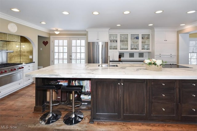 kitchen with ornamental molding, white cabinetry, dark brown cabinetry, a sink, and stainless steel refrigerator