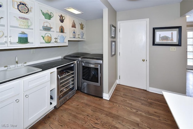 kitchen with beverage cooler, dark wood-type flooring, a sink, white cabinets, and washing machine and clothes dryer