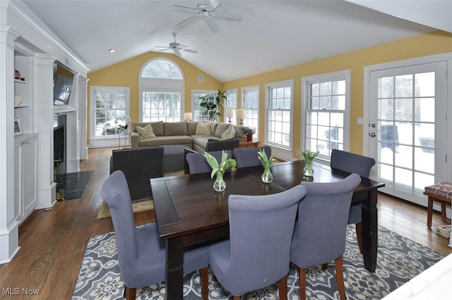 dining area with a fireplace with flush hearth, vaulted ceiling, ceiling fan, and wood finished floors