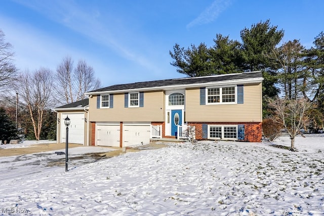 raised ranch featuring a garage and brick siding