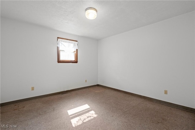 empty room featuring carpet, baseboards, and a textured ceiling