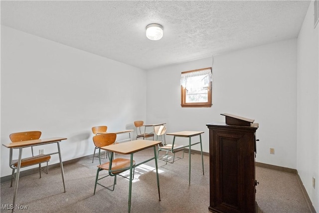 office space featuring carpet floors, visible vents, a textured ceiling, and baseboards