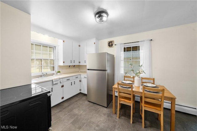 kitchen featuring light countertops, freestanding refrigerator, white cabinetry, a sink, and black / electric stove