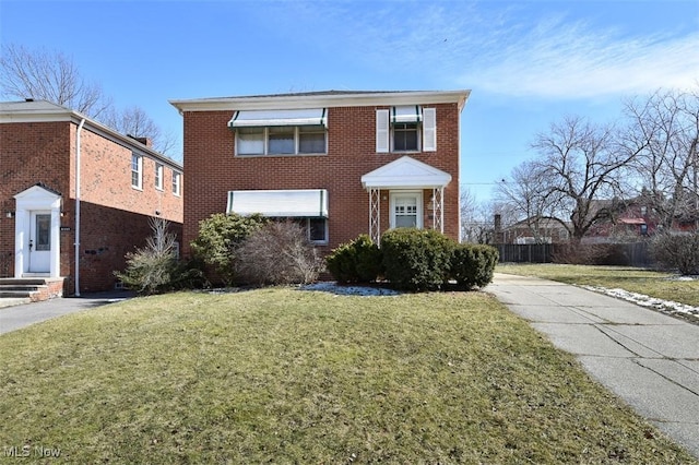 traditional home with a front yard, fence, and brick siding