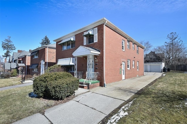 view of front of home featuring a detached garage, a front lawn, an outbuilding, and brick siding