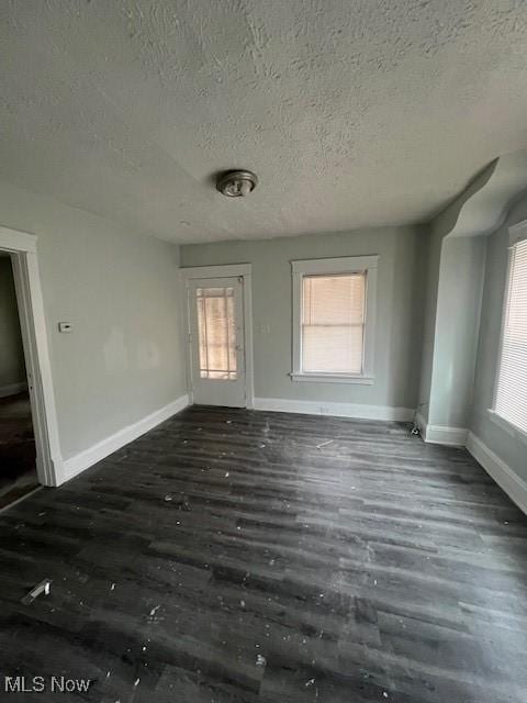 spare room featuring a textured ceiling, baseboards, and wood finished floors