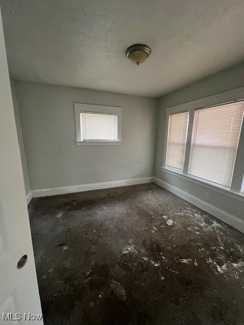 empty room with a textured ceiling and baseboards