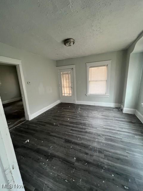 unfurnished room featuring a textured ceiling, baseboards, and wood finished floors