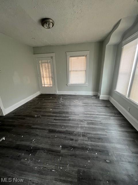 interior space with dark wood-style flooring, baseboards, and a textured ceiling