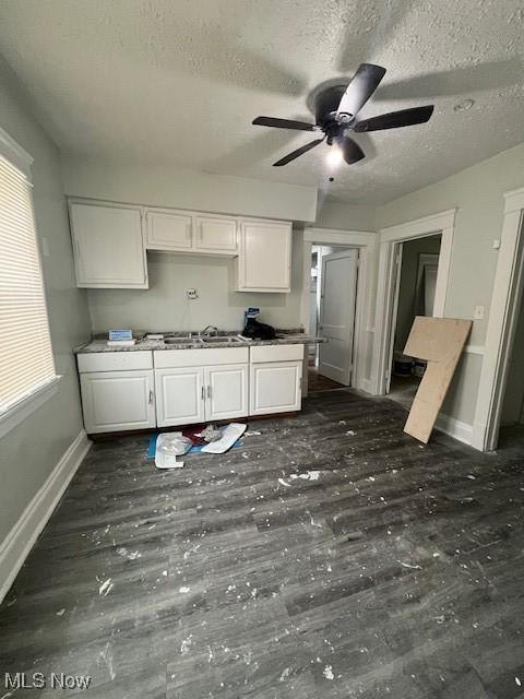kitchen with a textured ceiling, baseboards, a ceiling fan, and white cabinets