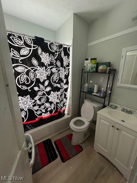 full bath featuring shower / bath combo, toilet, wood finished floors, a textured ceiling, and vanity