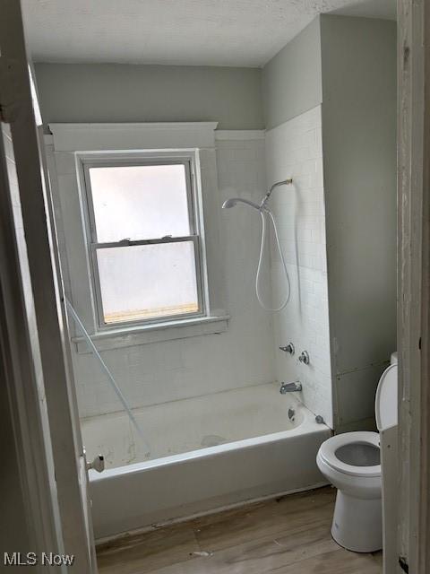 bathroom with toilet, wood finished floors, and washtub / shower combination