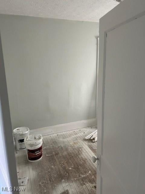 empty room featuring a textured ceiling, baseboards, and hardwood / wood-style flooring