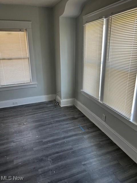 empty room featuring dark wood-style flooring and baseboards