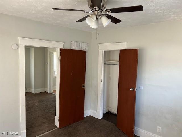 unfurnished bedroom featuring a closet, carpet, a textured ceiling, and baseboards