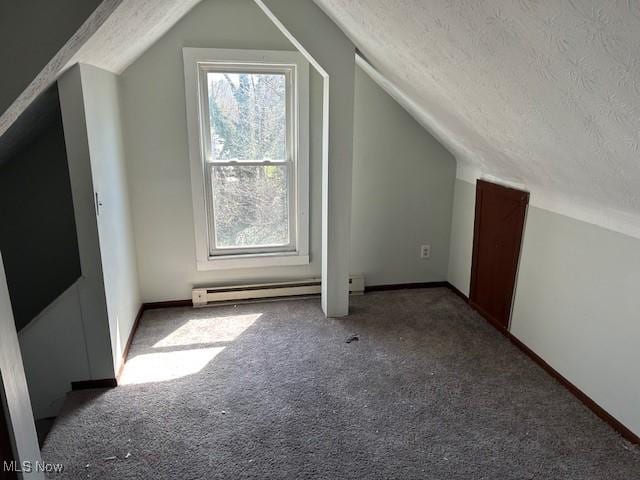 additional living space featuring baseboards, a textured ceiling, vaulted ceiling, carpet flooring, and a baseboard heating unit