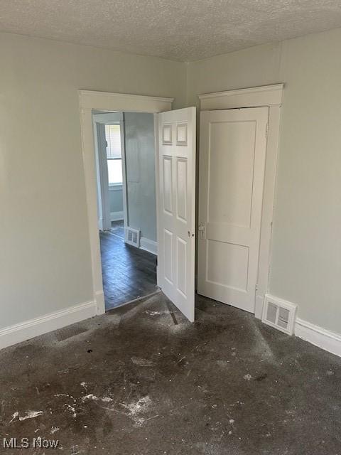 empty room featuring visible vents, baseboards, and a textured ceiling