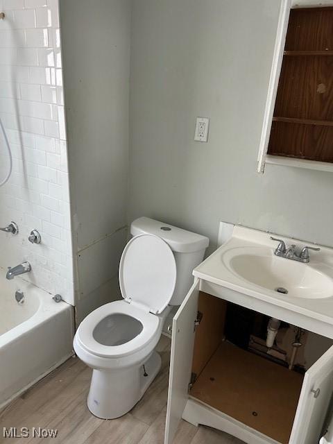 bathroom featuring toilet, wood finished floors, vanity, and shower / bathing tub combination