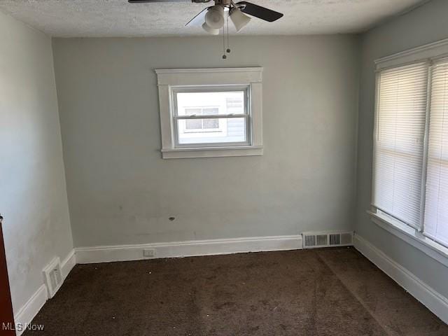 carpeted spare room featuring visible vents, ceiling fan, baseboards, and a textured ceiling