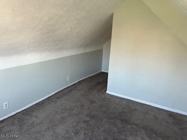 bonus room with baseboards, a textured ceiling, dark colored carpet, and lofted ceiling