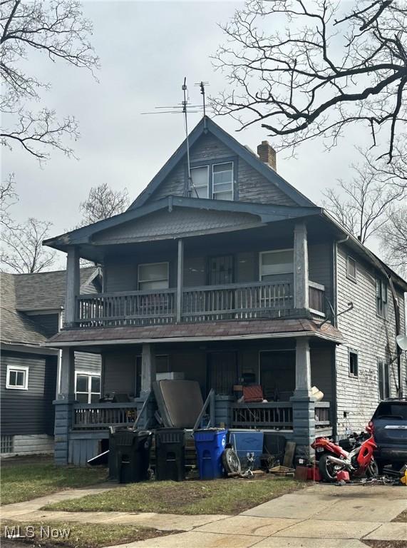 american foursquare style home with covered porch and a chimney